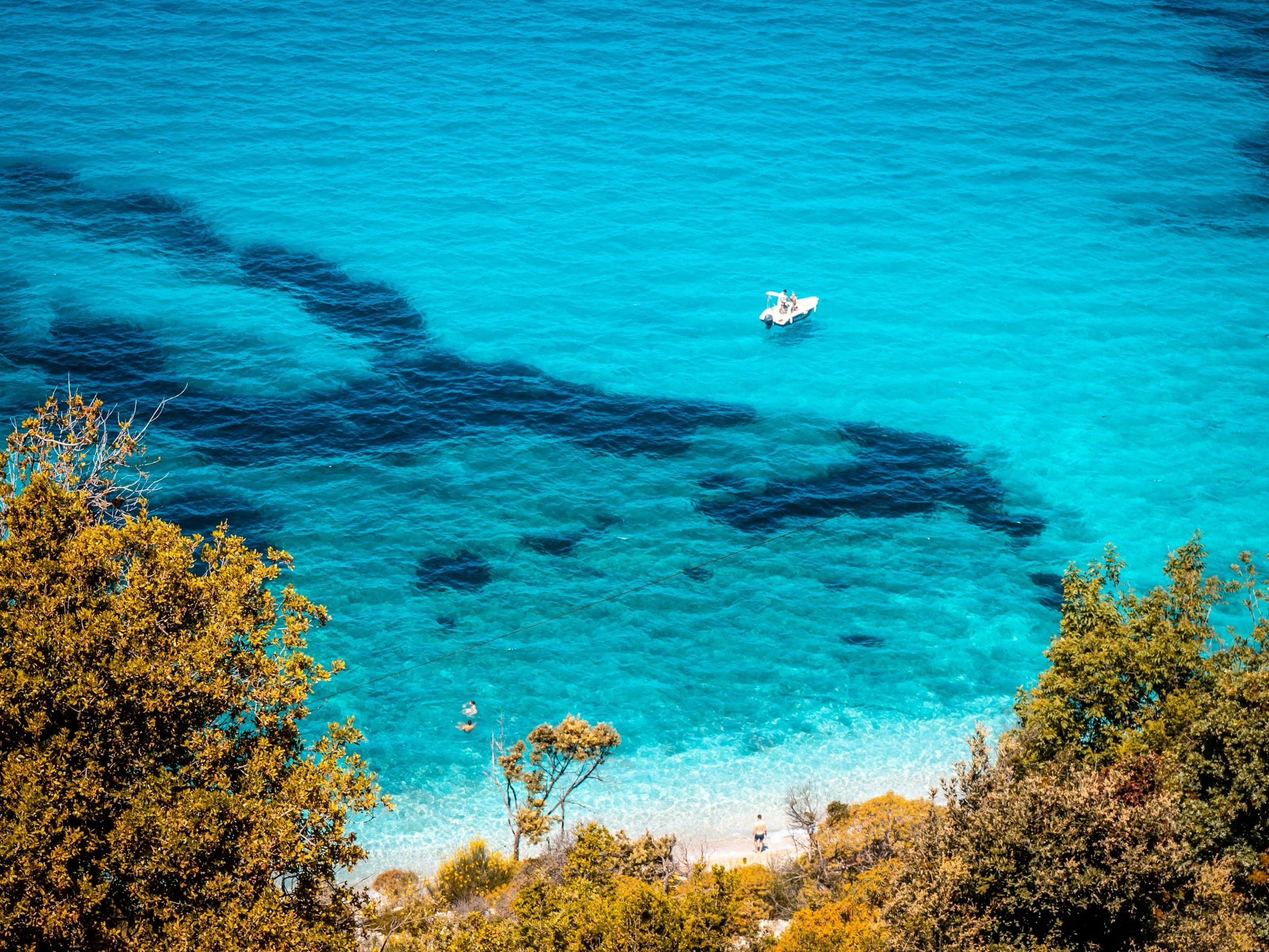 Ujë i kaltër dhe një varkë pranë bregut në Rivierën Shqiptare